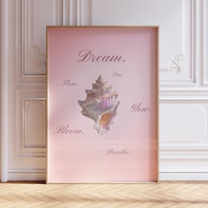 May include: A framed vertical wall art print featuring a light pink background with a central iridescent seashell. The text Dream, Sea, Flow, Glow, Bloom, and Breathe is printed in a dark script font around the shell on the pink surface.