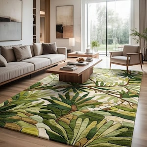 Può includere: Un soggiorno moderno con un grande tappeto rettangolare con un motivo a foglie tropicali verdi e beige. Il tappeto è il punto focale, completato da un divano chiaro, un tavolino in legno e una poltrona neutra. Grandi finestre.