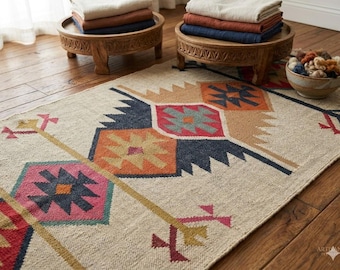 May include: A beige and multi-colored patterned rug with geometric designs. The rug features a central design with orange, blue, and red shapes. Two wooden stands with folded textiles are in the background. A bowl of yarn sits nearby.