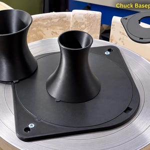May include: A black pottery wheel chuck system featuring a flat square baseplate with a central flared cone attachment, a secondary detached cone, and a separate baseplate component labeled with the text Chuck Baseplate only.