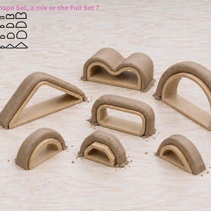May include: Seven geometric shapes made of light wood with a textured, matte grey clay-like coating on the top edges. The shapes include arches, triangles, and rectangular forms. Text at the top reads: Choose a Shape Set, a mix or the Full Set 7 shapes.
