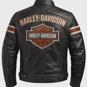 Może przedstawiać: Czarna skórzana kurtka z logo i napisem Harley-Davidson na plecach. Projekt zawiera poziome paski na rękawach w kolorze kremowym i pomarańczowym, stójkę oraz zamki błyskawiczne przy mankietach. Na plecach widnieje nazwa marki dużymi literami nad kultowym emblematem tarczy.