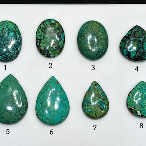 Può includere: Otto cabochon di turchese lucidati disposti su due file, numerati da uno a otto. Le pietre mostrano varie tonalità di verde e blu con motivi a matrice scura, caratterizzate da forme ovali e a goccia con superfici lisce e riflettenti.