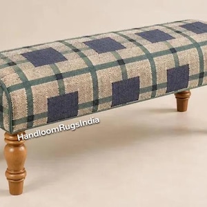 May include: A rectangular bench featuring a woven fabric upholstery with a plaid pattern in shades of beige, dark blue, and green. The bench is supported by four turned wooden legs in a medium brown finish. The text HandloomRugsIndia is visible.