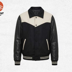 May include: A black and cream varsity jacket with leather sleeves. The jacket features a cream-colored yoke and collar, with black leather sleeves and a black body. It has two front pockets and a striped hem and cuffs.