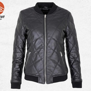 Puede incluir: Chaqueta bomber de cuero negro acolchada con cremallera, dos bolsillos laterales y puños y dobladillo de canalé. La chaqueta tiene un patrón de diamantes y un cuello negro. El logotipo "PRIMECUT JACKET SHOP" está en la esquina superior izquierda.