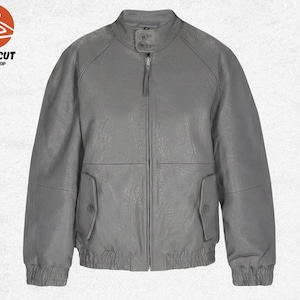 Puede incluir: Chaqueta de cuero gris con cuello alzado, cremallera frontal y dos bolsillos delanteros. La chaqueta tiene puños y dobladillo de canalé. El logotipo "PRIMECUT JACKET SHOP" está en la esquina superior izquierda.
