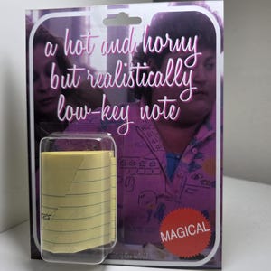 May include: A clear plastic package containing a roll of yellow sticky notes with blue lines. The packaging features the text "a hot and horny but realistically low-key note" and a red "MAGICAL" sticker.