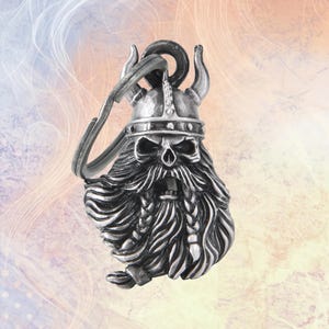 May include: A silver-toned metal keychain featuring a detailed skull wearing a horned helmet with a long, flowing beard and braided mustache. The keychain includes a circular metal ring for attachment. The text HaniaLeather is visible below.
