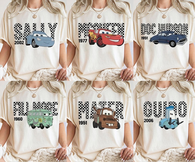 May include: Cream-coloured t-shirts featuring cartoon car characters from the film Cars. Each shirt has a different character name in a checkered font, with the year the character was introduced.
