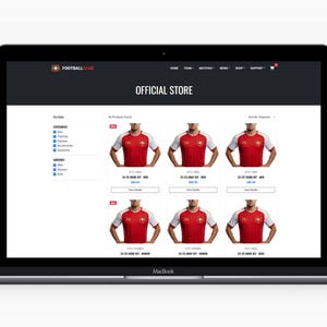 May include: A laptop screen showing a football club's official online store. The website features red and white football shirts. The words "OFFICIAL STORE" are displayed at the top. The laptop is on a white surface.