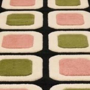 以下が含まれることがあります： 黒い背景に丸みを帯びた四角形が繰り返される模様が特徴の長い長方形のランナーラグ。各四角形には、柔らかいピンクとセージグリーンの色が交互に配置された無地の中心ブロックを囲む、厚いクリーム色の縁取りが施されています。