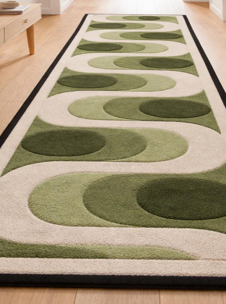 Puede incluir: Una alfombra larga y rectangular con un patr&oacute;n repetitivo de formas verdes y blanquecinas. La alfombra tiene un borde negro y est&aacute; colocada sobre un suelo de madera. El dise&ntilde;o presenta c&iacute;rculos superpuestos y l&iacute;neas curvas.