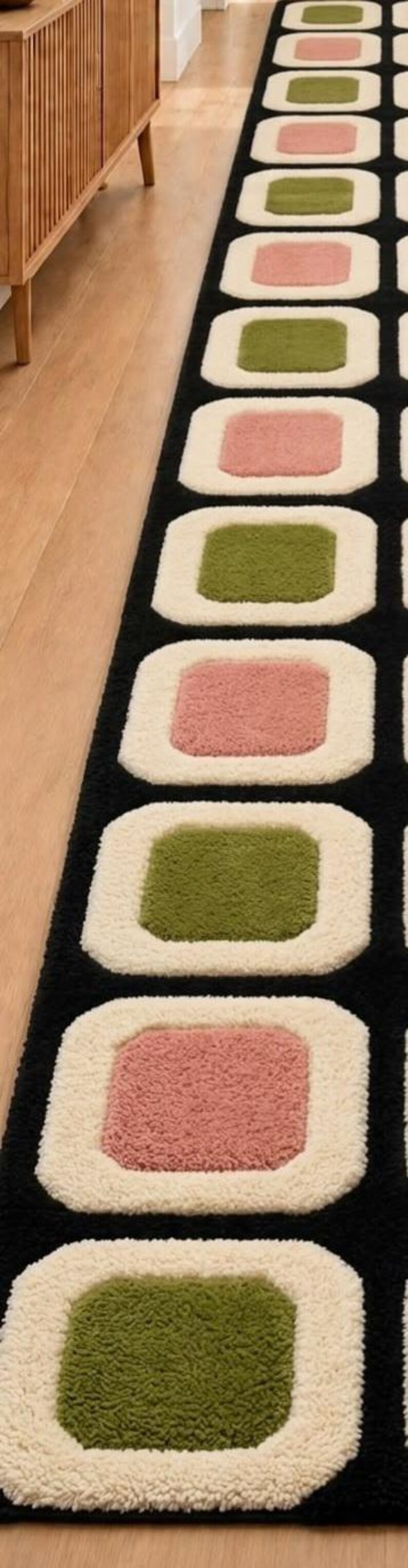 以下が含まれることがあります： 黒い背景に丸みを帯びた四角形が繰り返されるデザインの長いランナーラグ。各四角形は、厚みのあるクリーム色の縁取りが特徴で、中央部分は落ち着いたオリーブグリーンとダスティローズピンクが交互に配置されています。