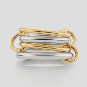 Könnte beinhalten: Ein moderner Ring mit einem verbundenen Design aus abwechselnd gold- und silberfarbenem Metall. Der Ring hat eine geometrische Form und eine polierte Oberfläche, geeignet für den Alltag.