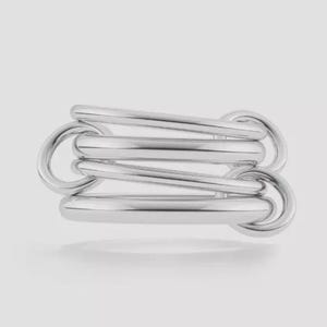 Peut inclure: Une bague argentée au design unique. La bague présente plusieurs barres arrondies et des maillons circulaires, créant un aspect superposé et texturé. Le métal a une surface polie et réfléchissante.