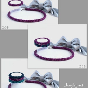 May include: Three sets of purple and teal beaded necklaces and bracelets. The necklaces are all the same length and the bracelets are all the same size. The jewelry is displayed on a white surface with a gray satin bow.