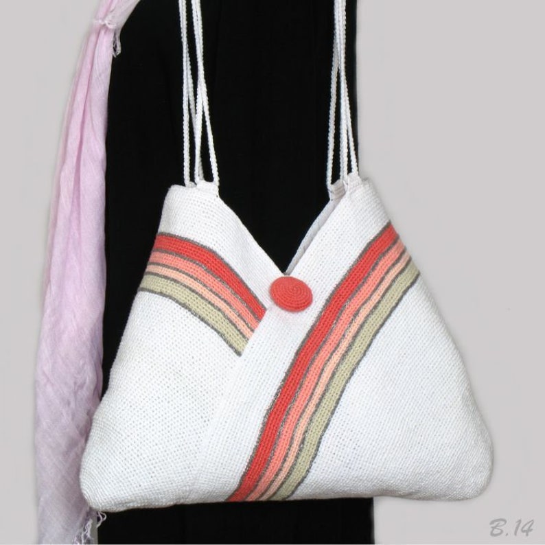 May include: White crocheted tote bag with a pink, orange, and beige striped design. The bag has a large, coral-colored button.