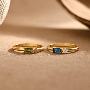 May include: A white ceramic mug with a black handle and the text "But First, Coffee" in a bold, black font. The mug is filled with a dark liquid, likely coffee, and sits on a light-colored surface.