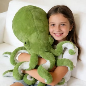 May include: A large, plush green octopus stuffed animal with white accents on the tentacles. The soft toy is made of a fuzzy material and has a friendly, cartoonish appearance. The octopus is being held.