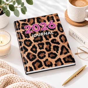 Puede incluir: Un diario rectangular con un patrón de estampado de leopardo marrón y negro en la portada. El texto 2026 está impreso en grandes números rosas y blancos en la parte superior, con la palabra JOURNAL impresa en letras mayúsculas blancas debajo.