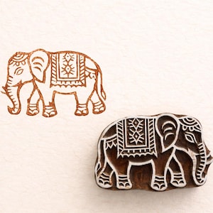 May include: Two wooden elephant stamps. One is a detailed outline of an elephant with decorative patterns. The other is a solid, carved wooden block of an elephant with intricate designs, ready for printing.