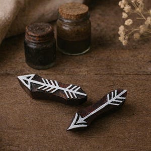 May include: A white ceramic mug with a black handle and the text "But First, Coffee" in a bold, black font. The mug is set against a blurred background. The mug appears to be approximately 10 cm tall.