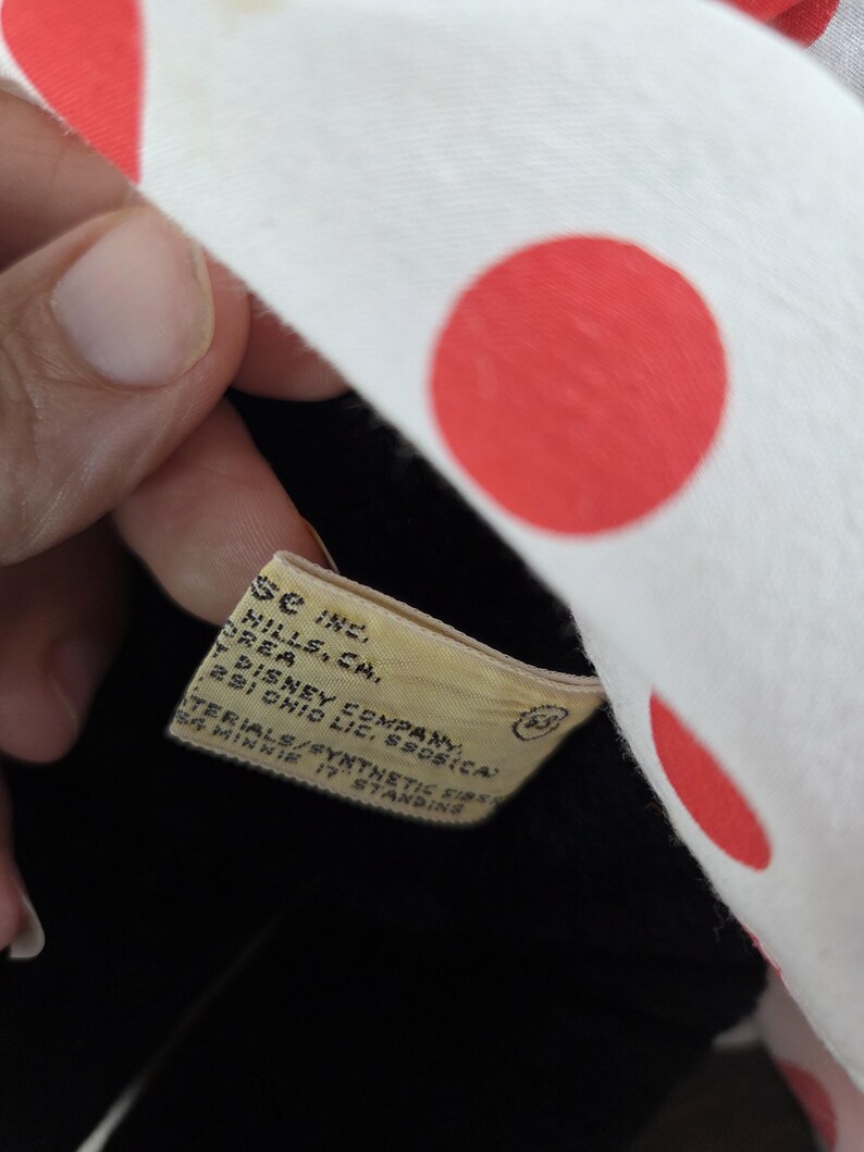 Pu&ograve; includere: Un peluche di Minnie Mouse con un fiocco bianco a pois rossi. L'etichetta recita "PREA DISNEY COMPANY 291 OHIO LIC. 55051CA". Il giocattolo &egrave; in bianco e nero e sembra vintage.