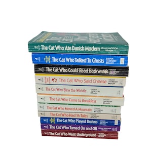 May include: A stack of 12 paperback books with colourful covers. The books are all part of the "The Cat Who..." series by Lilian Jackson Braun. The titles include "The Cat Who Ate Danish Modern", "The Cat Who Talked To Ghosts", "The Cat Who Could Read Backwards", "The Cat Who Said Cheese", "The Cat Who Blew the Whistle", "The Cat Who Came to Breakfast", "The Cat Who Moved A Mountain", "The Cat Who Had 14 Tales", "The Cat Who Played Brahms", "The Cat Who Turned On and Off", and "The Cat Who Went Underground".