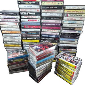 以下が含まれることがあります： カントリーミュージックのアーティストをフィーチャーした、ヴィンテージのカセットテープとCDのコレクション。 「Country's Greatest Hits」、「Highway 101」、Holly Dunnのアルバムなどのタイトルが含まれています。 メディアは透明なプラスチックケースに入っており、白い背景に積み重ねられています。
