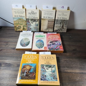 May include: A collection of eight paperback books by J.R.R. Tolkien, including "The Hobbit" and "The Lord of the Rings" trilogy. The books have yellow covers with illustrations and text.