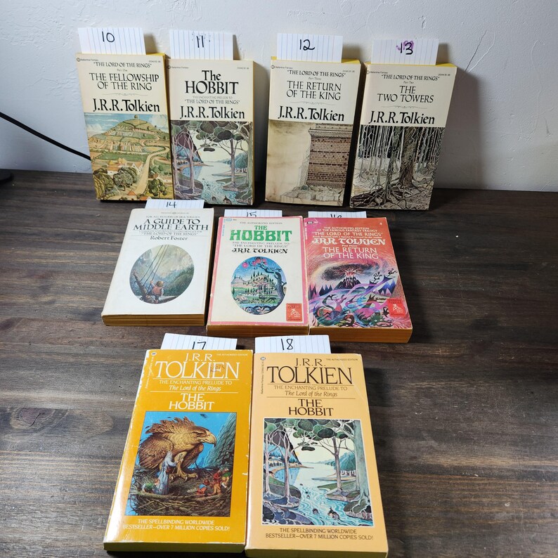 May include: A collection of eight paperback books by J.R.R. Tolkien, including "The Hobbit" and "The Lord of the Rings" trilogy. The books have yellow covers with illustrations and text.