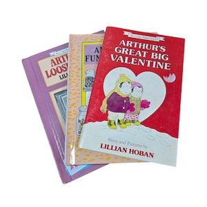 May include: Three children's books titled Arthur's Great Big Valentine, Arthur's Loose Tooth, and Arthur's Funny Money. The books feature colorful illustrated covers with characters in winter clothing, heart shapes, and text by Lillian Hoban.