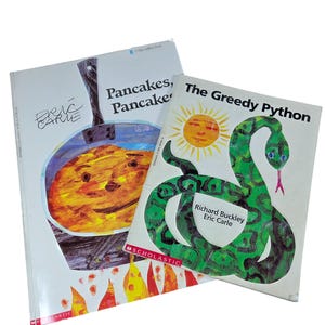 May include: Two children's books, "Pancakes, Pancakes" and "The Greedy Python." The "Pancakes" book features a colorful illustration of a pancake with a face. "The Greedy Python" shows a green snake with a yellow sun.