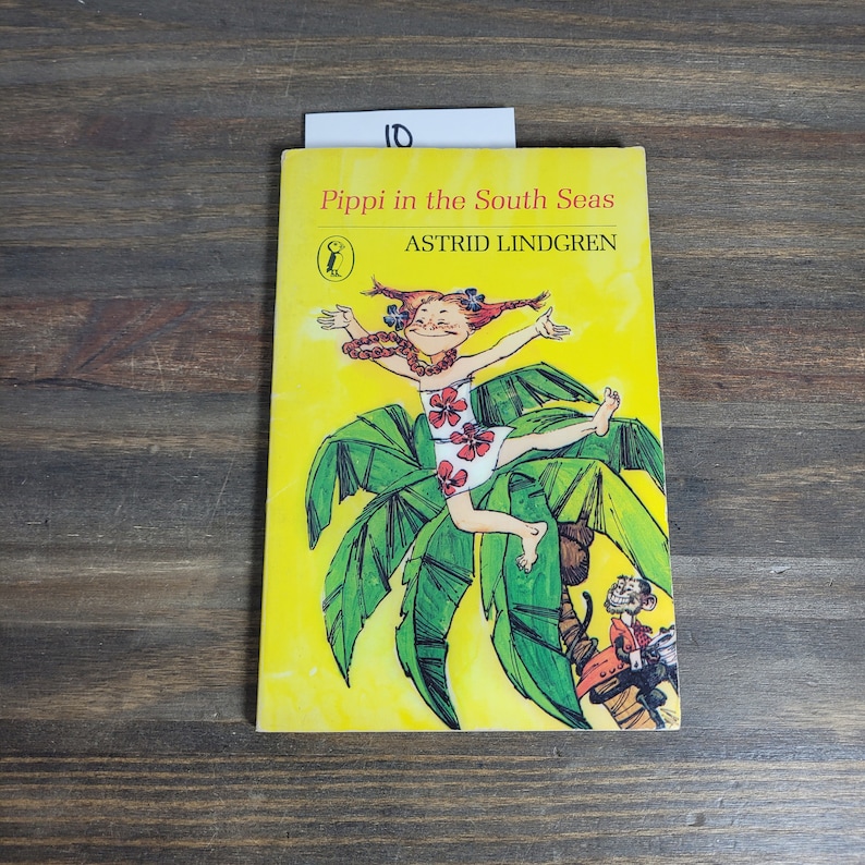 Puede incluir: Una portada de libro amarilla con una ilustraci&oacute;n de dibujos animados de una ni&ntilde;a con cabello rojo y un mono. El t&iacute;tulo del libro es "Pippi en los mares del sur" de Astrid Lindgren.