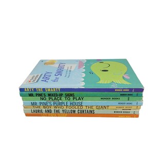 Könnte beinhalten: Ein Stapel alter Kinderbücher mit farbenfrohen Einbänden. Zu den Titeln gehören "Arty the Smarty", "Mr. Pine's Mixed-Up Signs" und "No Place to Play". Die Bücher stammen aus der "Wonder Books"-Reihe und haben ein hellblaues, grünes und oranges Farbschema.
