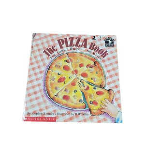 May include: A paperback book titled The Pizza Book: Fun, Facts, a Recipe—the Works! by Stephen Krensky and illustrated by R.W. Alley. The cover features a cartoon illustration of a sliced pizza on a red and white checkered tablecloth background.