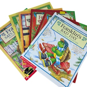 Op de afbeelding: Een stapel kinderboeken met Franklin de Schildpad. De boeken hebben kleurrijke covers met illustraties van Franklin in verschillende scènes, waaronder een winters tafereel. De boeken zijn uitgegeven door Scholastic.