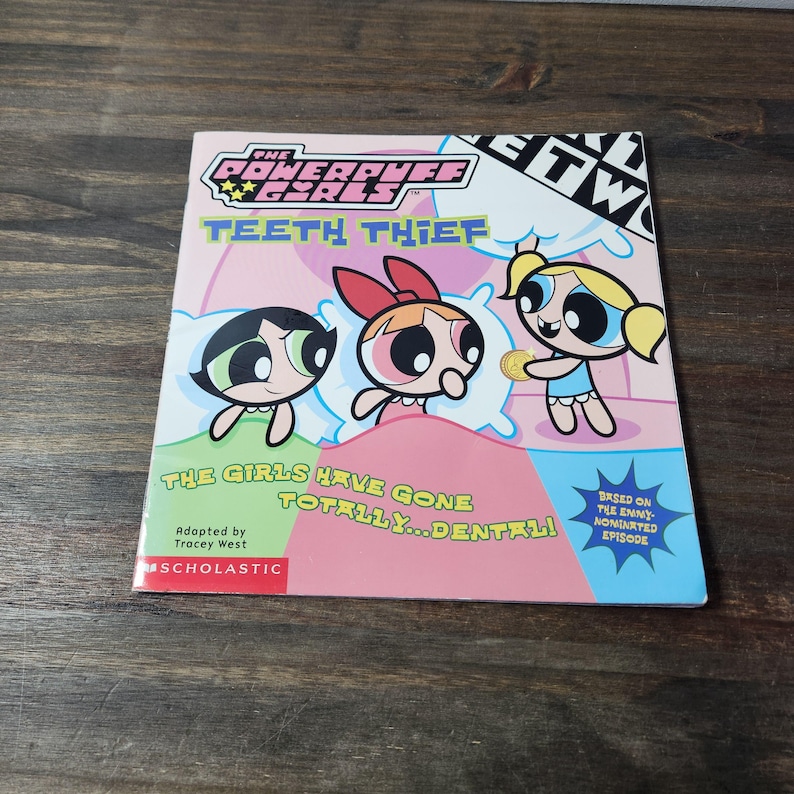 May include: A pink, green, and blue book cover featuring the Powerpuff Girls cartoon characters. The title of the book is "Teeth Thief" and the text "The girls have gone totally... dental!" is below the characters. The book is adapted by Tracey West and published by Scholastic.
