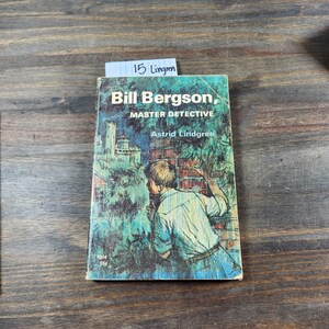 Puede incluir: Un libro de bolsillo vintage titulado "Bill Bergson, maestro detective" de Astrid Lindgren. La portada presenta una ilustraci&oacute;n de un ni&ntilde;o peque&ntilde;o mirando por encima de un muro de ladrillos.
