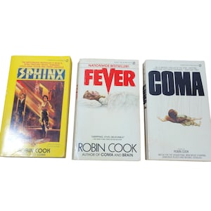Può includere: Tre libri tascabili con copertine gialle, bianche e bianche. I titoli sono "Sphinx", "Febbre" e "Coma". Tutti e tre i libri sono di Robin Cook, autore di "Coma" e "Brain".