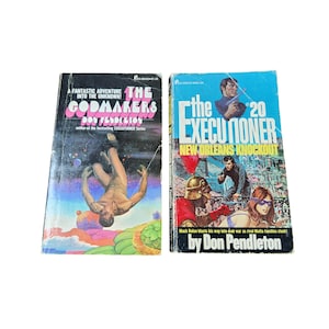 May include: Two paperback books, one with a blue cover and the other with a black cover. The blue book has the title "The Executioner" and the text "New Orleans Knockout". The black book has the title "The Godmakers" and the text "A Fantastic Adventure Into The Unknown!"