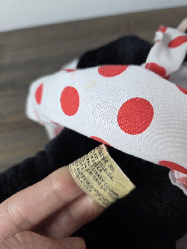 Pu&ograve; includere: Un peluche nero con un fiocco bianco a pois rossi. L'etichetta recita "Walt Disney Company" e "Minnie 17 Star". Il giocattolo &egrave; realizzato con materiali sintetici.