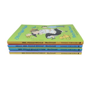 May include: A stack of four colorful paperback books with the title "Mrs. Piggle-Wiggle" and the author "MacDonald". The books are in a rainbow of colors, with the top book being yellow, the second book being orange, the third book being blue, and the fourth book being light blue.