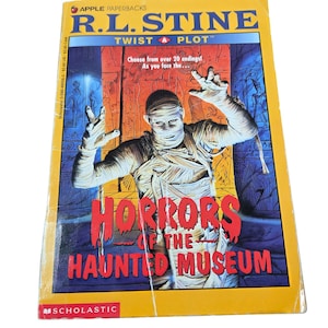May include: A paperback book titled "Horrors of the Haunted Museum" by R.L. Stine. The cover features a mummy with outstretched arms against a backdrop of an Egyptian tomb. The book is part of the "Twist-A-Plot" series.