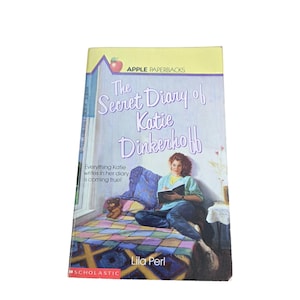 May include: A paperback book titled "The Secret Diary of Katie Dinkerhoff" by Lila Perl. The cover features an illustration of a girl writing in a diary. The book is part of the Apple Paperbacks series, published by Scholastic.