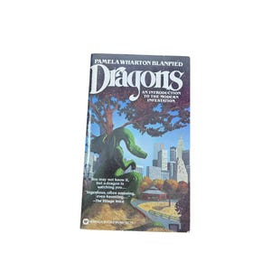 May include: A paperback book titled Dragons: An Introduction to the Modern Infestation by Pamela Wharton Blanpied. The cover features a green dragon perched on a hill overlooking a city skyline with trees, a small building, and text.
