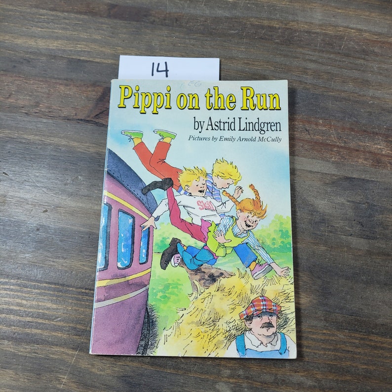 Puede incluir: Una portada de libro con el t&iacute;tulo "Pippi on the Run" de Astrid Lindgren. La portada presenta una ilustraci&oacute;n de ni&ntilde;os jugando en un tren.