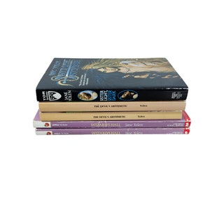 May include: A stack of five books by Jane Yolen. The top book is titled "Wicked Light" with a dark cover featuring a woman's portrait. Below are "Sister Light, Sister Dark" and "The Devil's Arithmetic". The bottom two books are "Wizard's Hall".