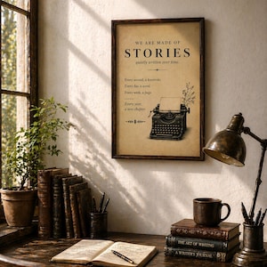 May include: A vintage-style print with the words "WE ARE MADE OF STORIES" and a typewriter illustration. The print is displayed above a desk with books, a lamp, and a mug. The scene creates a cosy, literary atmosphere.